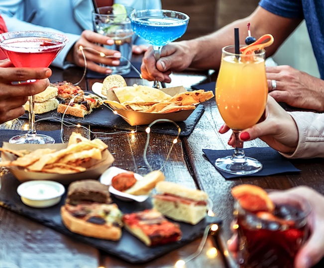 group dining together outside with an assortment of food and cocktails